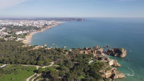 los exuberantes acantilados verdes de portimão sobre el mar azul, algarve, portugal - desde el aire