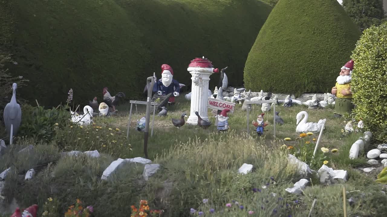 Gnome holding a carrot stands in a grassy field surrounded by other cheerful gnomes, creating a whimsical garden scene