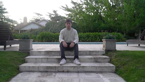 man walks on pool decking and sits on steps