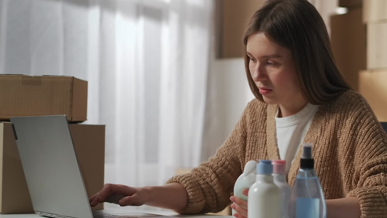 woman is working in small company of trading or producing household chemicals, filling information about products in laptop, medium portrait