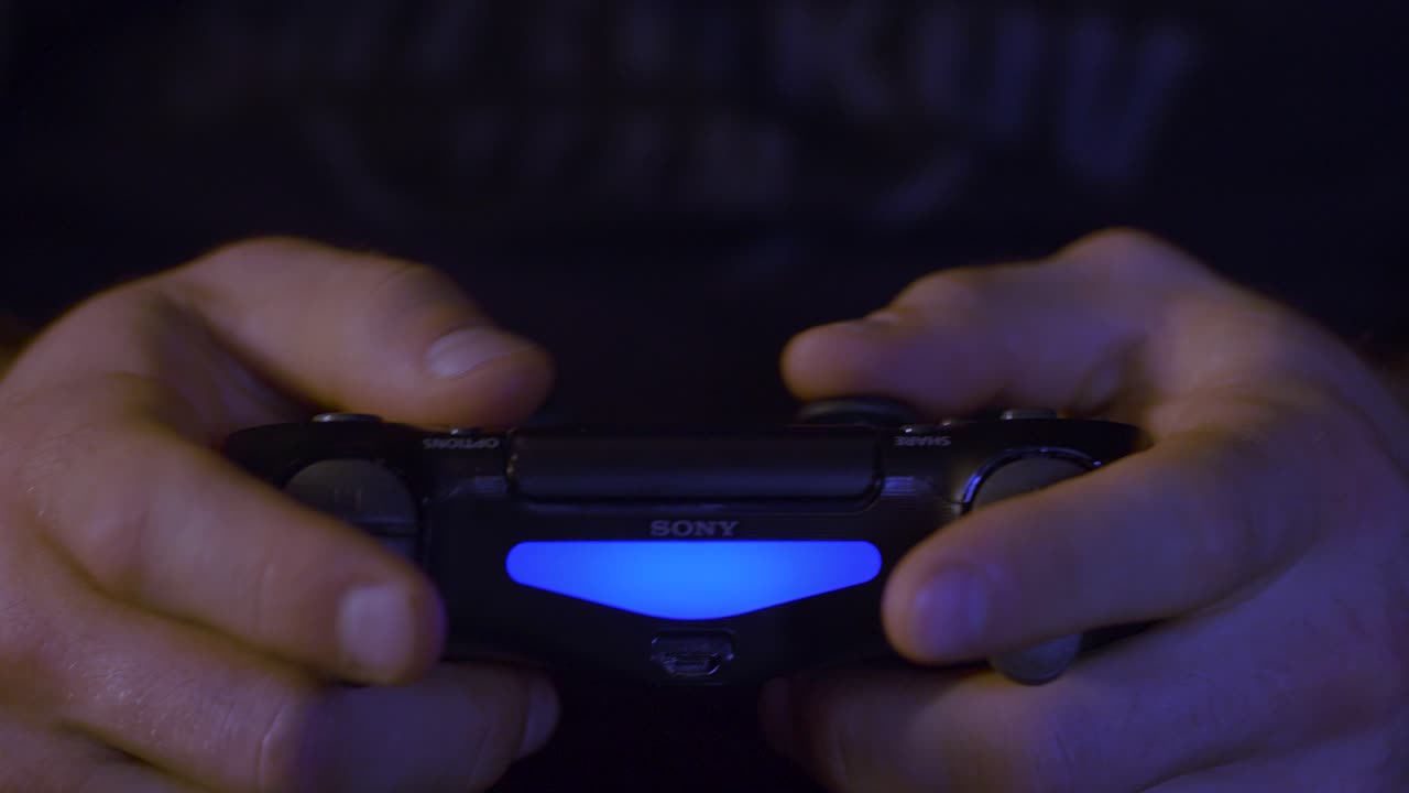 mani che tengono un controller playstation blu luminoso