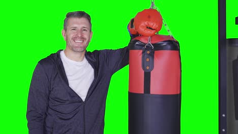smiling man leaning on a boxing bag