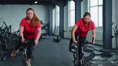 Gesunde-Kaukasische-Gruppe-Von-Frauen-Trainieren-Auf-Einem-Stationären-Fahrrad-Im-Fitnessstudio