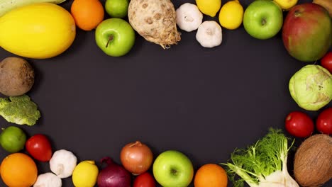 fresh fruits and vegetables making vibrant creative frame for text on black background. stop motion