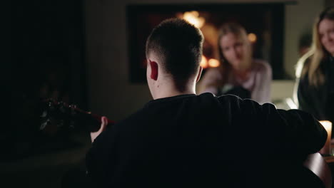 friends playing guitar by fireplace