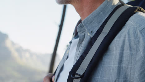 Animation-of-glowing-light-over-happy-senior-man-with-backpack-in-mountains