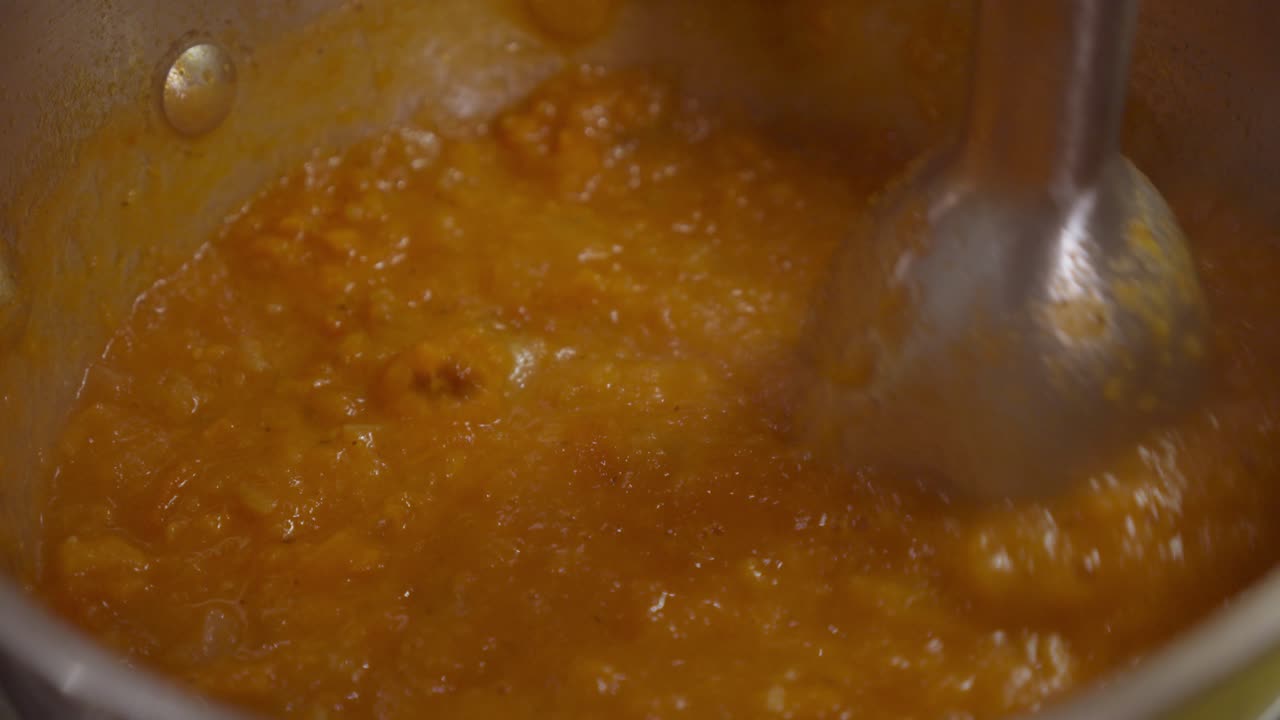 triturar los ingredientes de la sopa de verduras con una licuadora dentro de una olla caliente