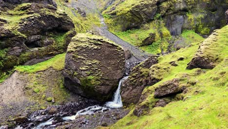 rocky mossy landscape and small flowing river with waterfall in iceland, handheld