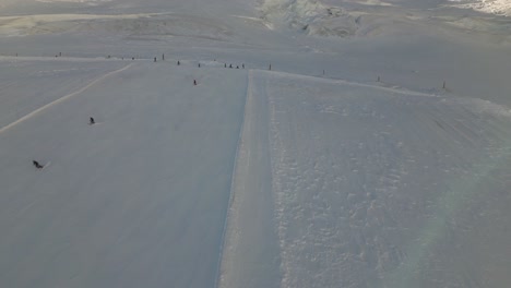 Vista-Aérea-De-Una-Pista-De-Esquí-Con-Esquiadores-Cuesta-Abajo,-Deportes-De-Invierno,-Paisaje-En-Los-Alpes