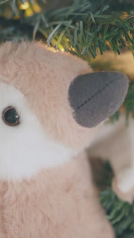 brown toy penguin used as decoration on beautiful christmas tree with artificial snow in room close view