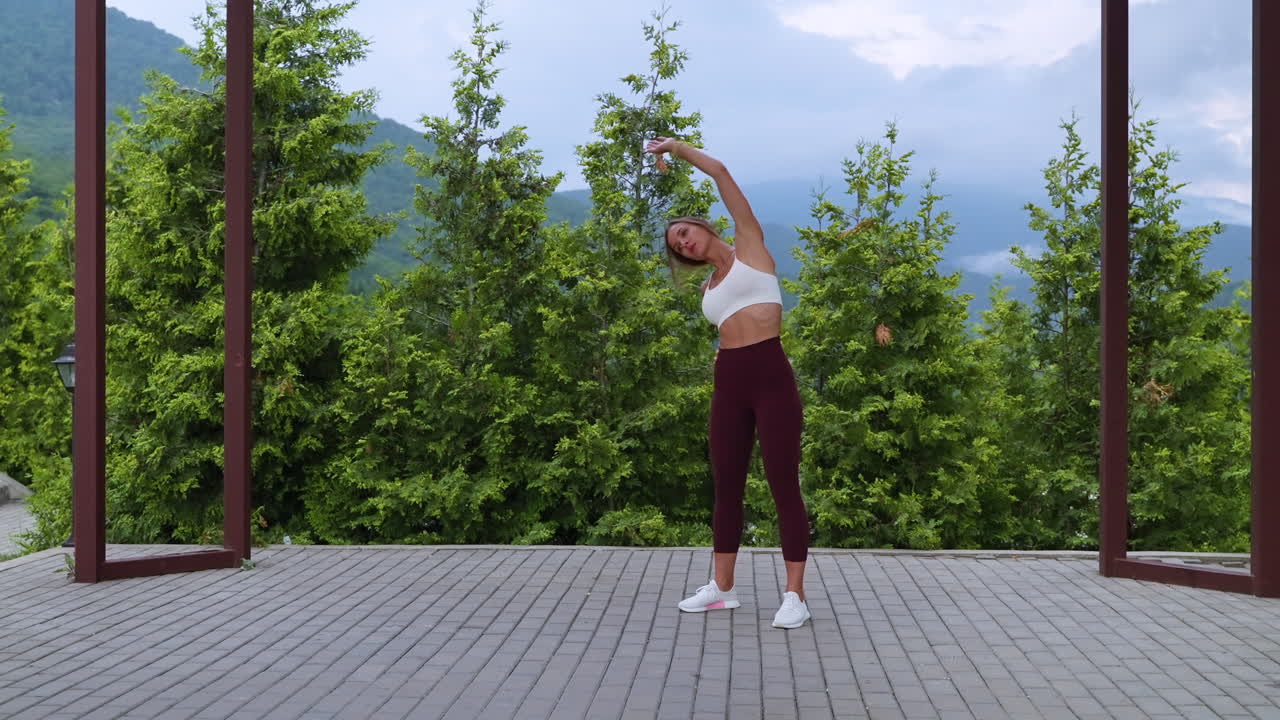 mujer estirándose al aire libre en un parque con vistas a las montañas