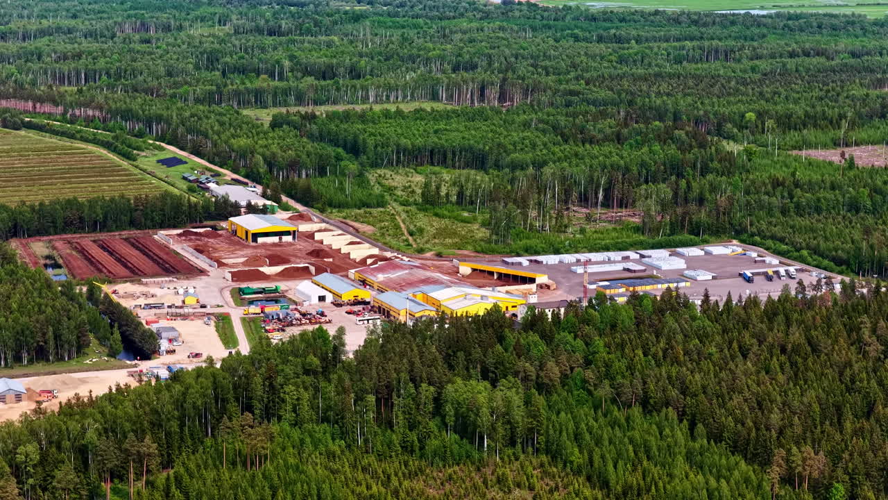 Peat factory complex with surrounding storage yards and forest landscape seen from above