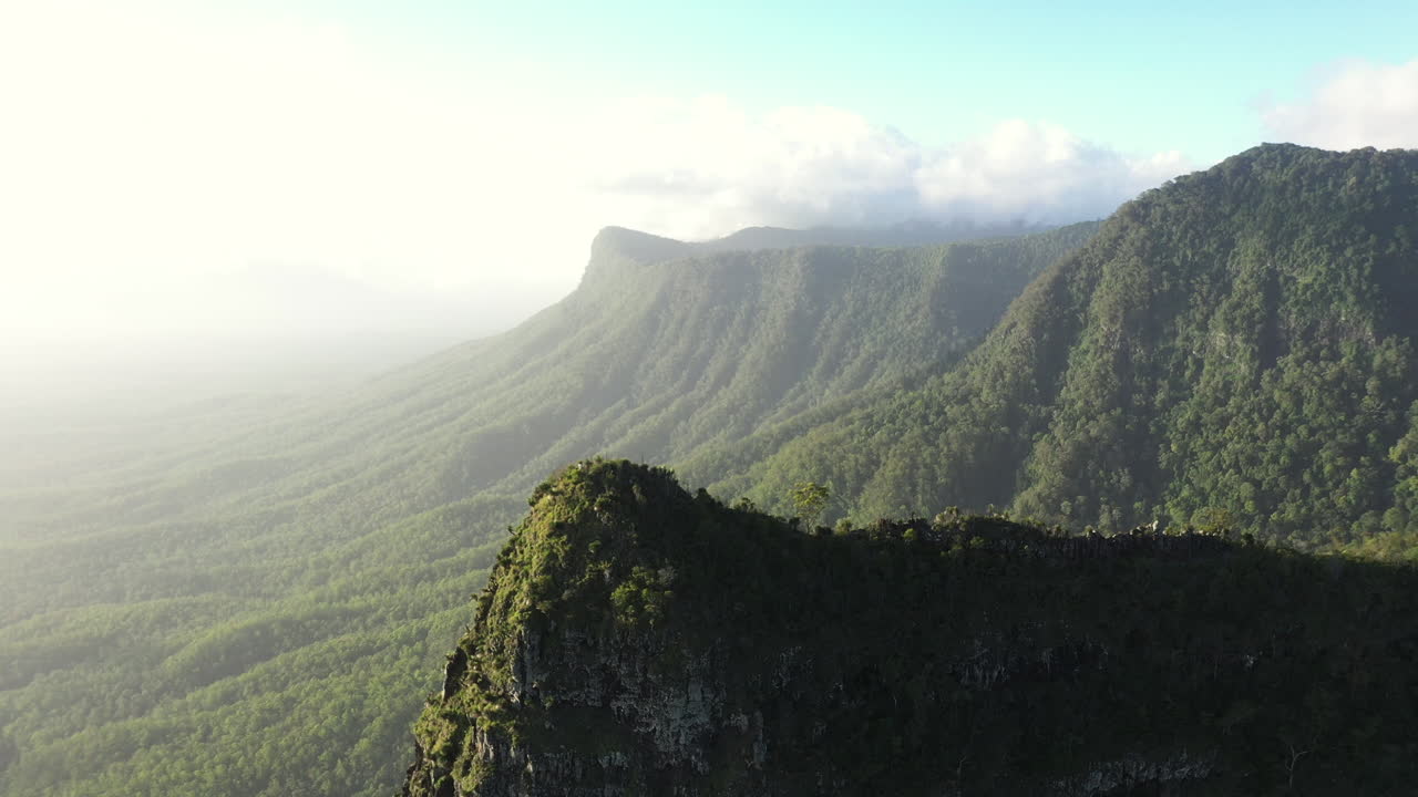 toma de dron de 4k de un pico de montaña y un hermoso paisaje cubierto de árboles durante la puesta de sol en el parque nacional border ranges, nueva gales del sur en australia