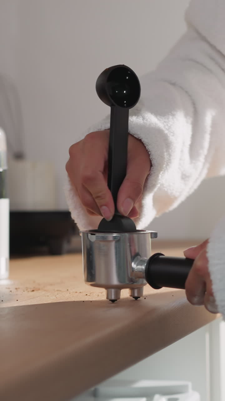 포타 필터 클로즈업에서 커피를 는 여자. 부드러운 욕조를 입은 여자가 집에서 에스프레소 가루로 컨테이너를 채운다. 에너지 음료 준비