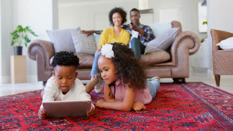 Front-view-of-cute-black-kids-using-digital-tablet-in-living-room-at--comfortable-home-4k