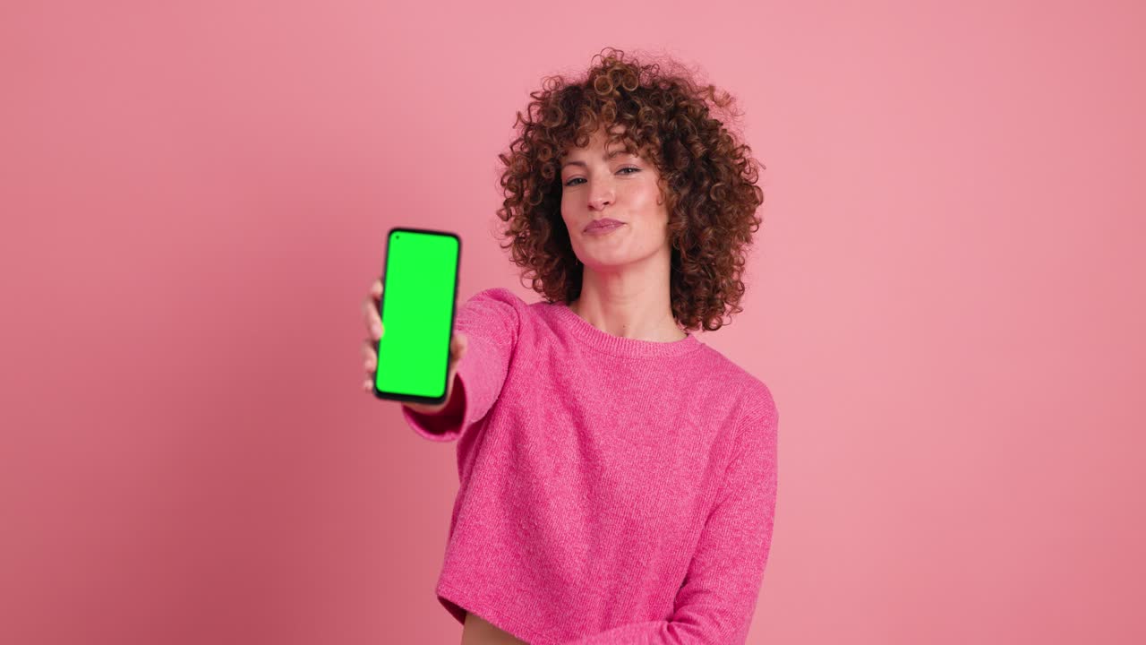 Happy woman showing mobile phone with chromakey in studio