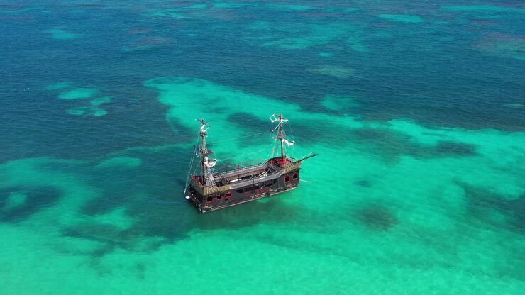 Pirate ship floating in caribbean sea. It is popular excursion for tourists. Dominican Republic. Aerial top view