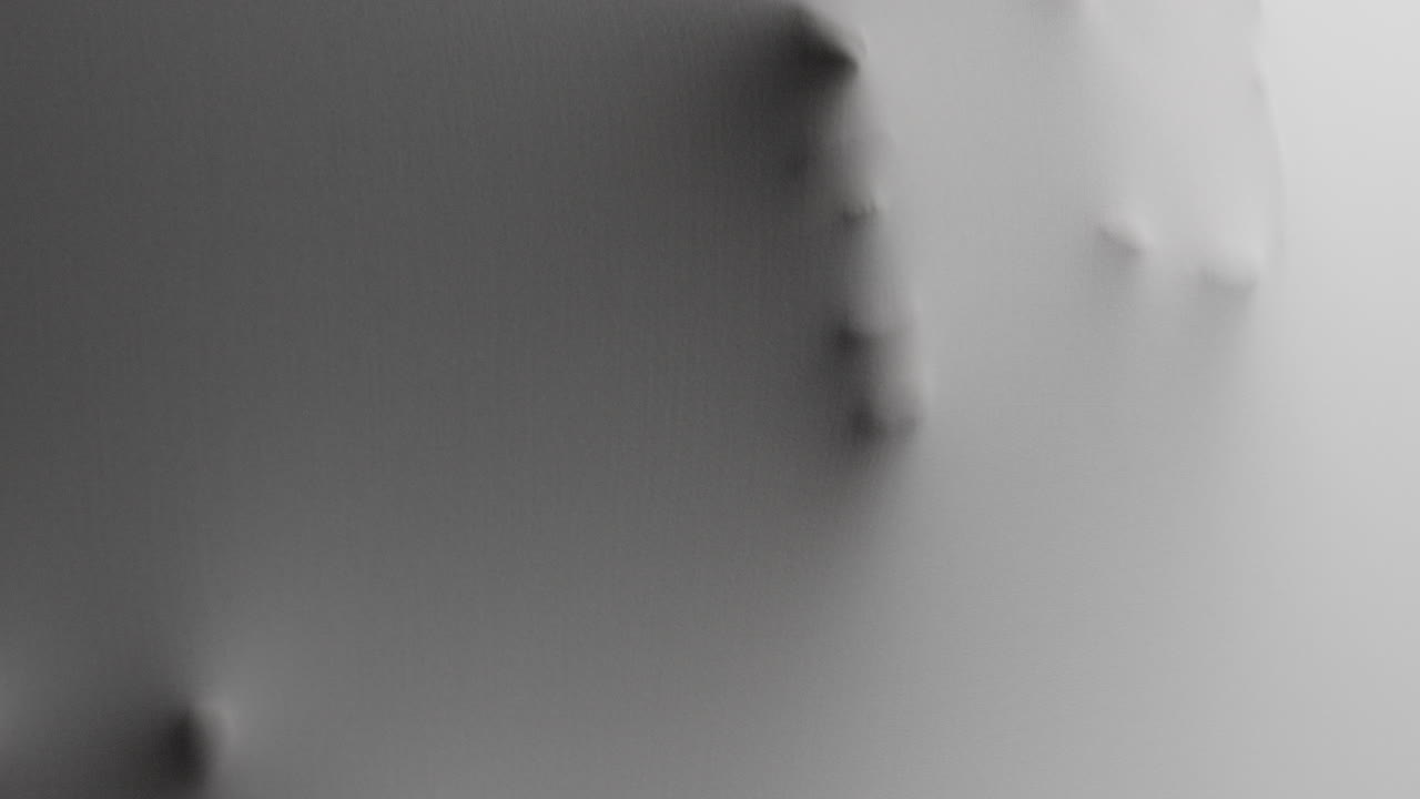 Creepy silhouettes of a woman's hands appears from the white surface