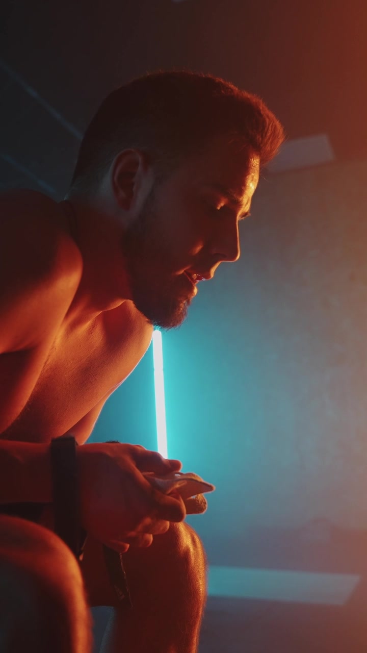 Sweaty Athlete Resting in a Dark Gym with Neon Lights