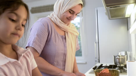 vista de cerca de la madre con el hijab y la hija en la cocina.