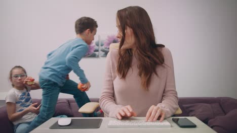 children have fun with working mom. female freelancer multitasking at home