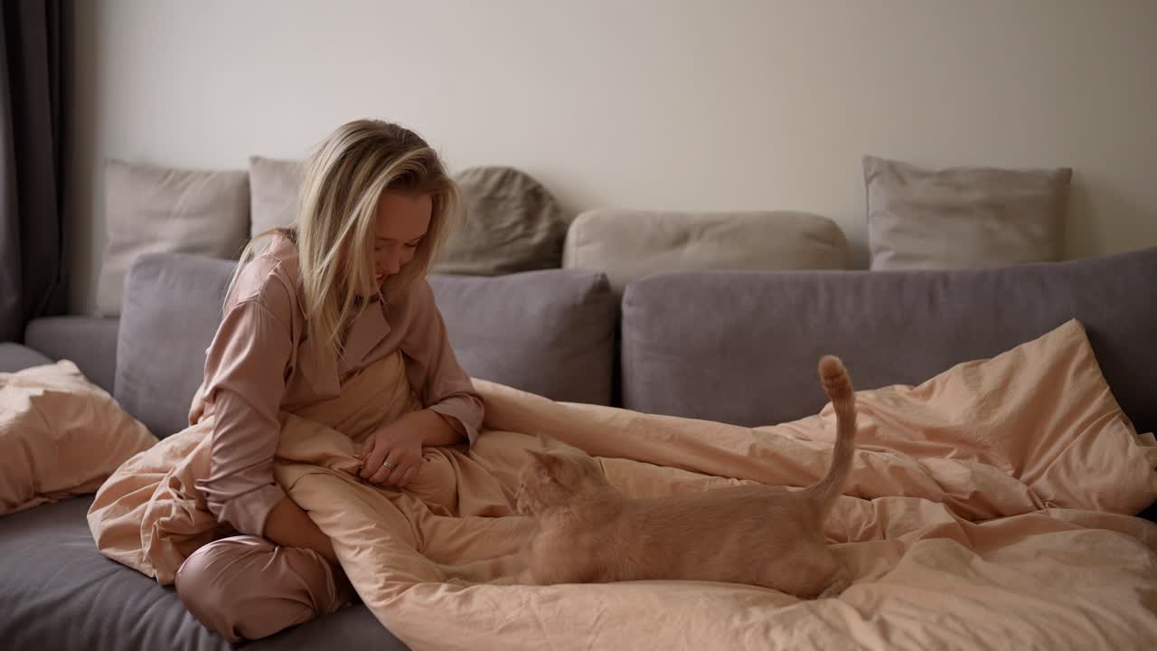 mujer y gato jugando en la cama