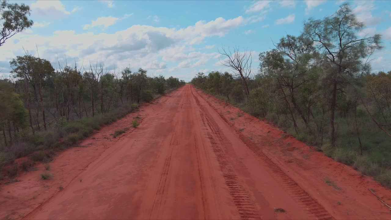 pista de tierra roja bordeada de matorrales y árboles en el interior de australia