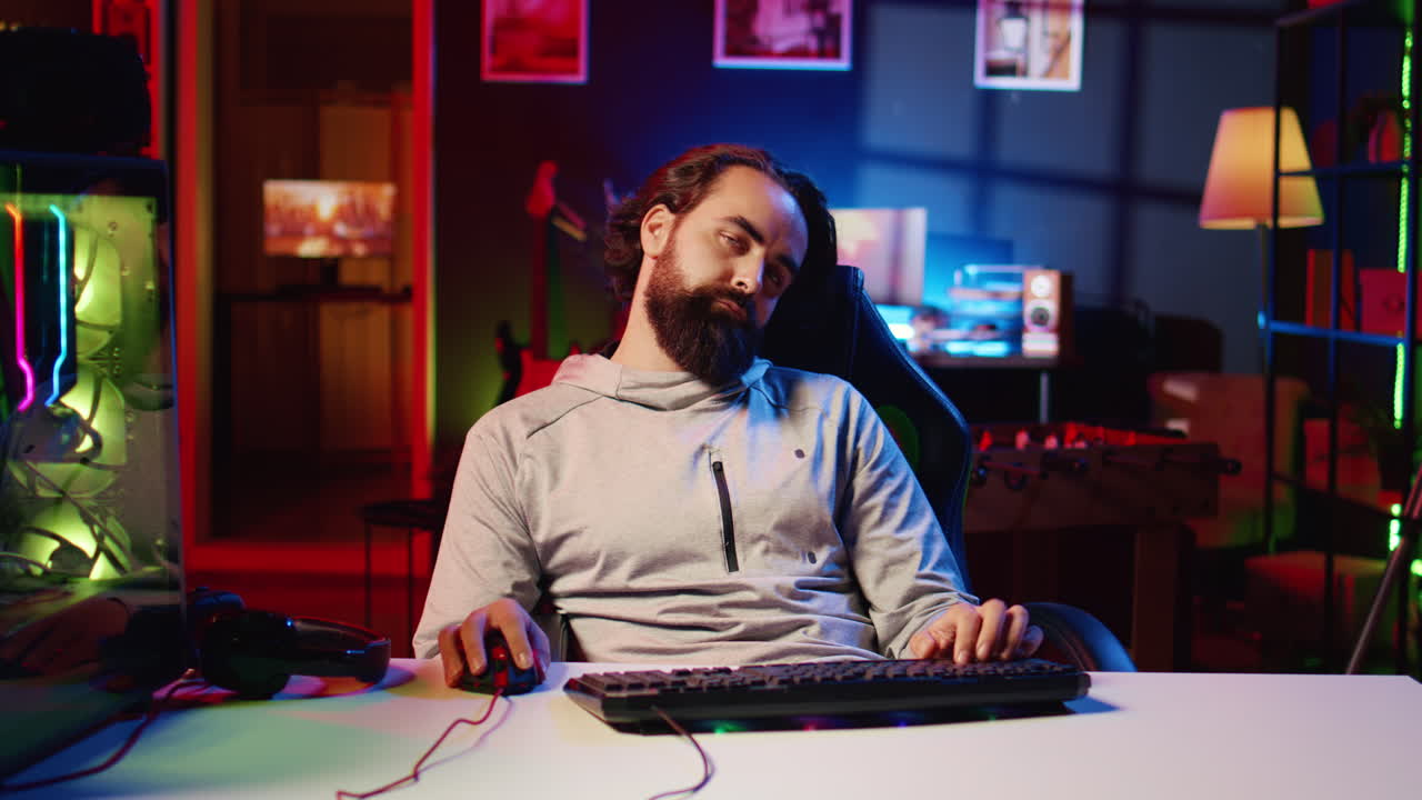Man feeling tired after working all day, struggling to stay awake while playing videogames