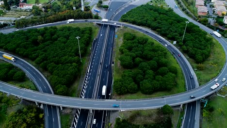 panoramic aerial view over highway interchange in france. only homes and grass fields around roads. cars and trucks driving on the roads.