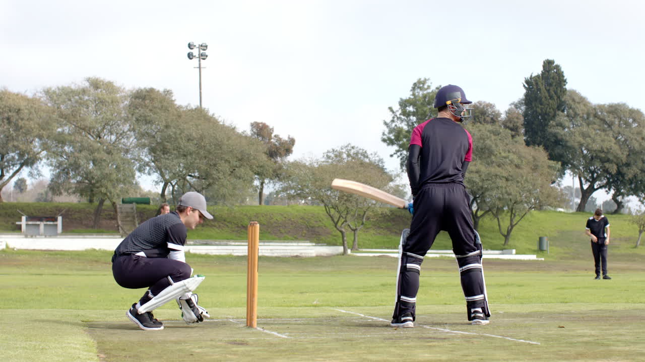 Two teams of multiracial male cricket players playing cricket on pitch