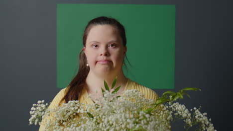 portrait of pretty girl with down syndrome holding flowers
