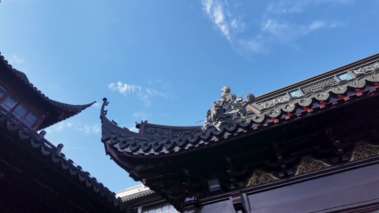 Cinematic slow motion close-up of ornate curved roof with dragon ridge and ceramic figures at Yu Garden Shanghai, blue sky background