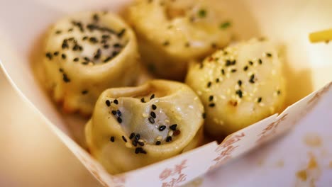 chopsticks picking up sesame-topped buns