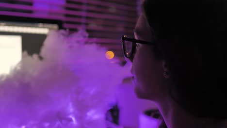 teenage girl using electronic cigarette in a room in front of computer at night