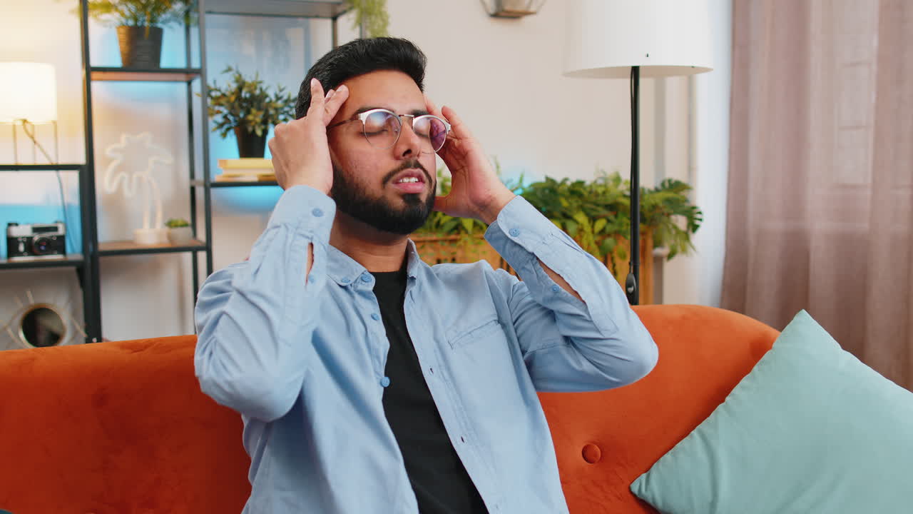 Sick indian man rubbing temples to cure headache problem suffering from tension migraine stress