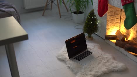 Laptop-at-Santa-Claus-workplace.-Close-up-of-computer-with-chroma-key-on-table.-Christmas-time,-holidays-and-celebrations-concept.-New-Year-tree-and-fireplace-on-background.