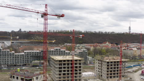 Steel-tower-cranes-at-construction-site-in-Prague-center,-aerial-tilt