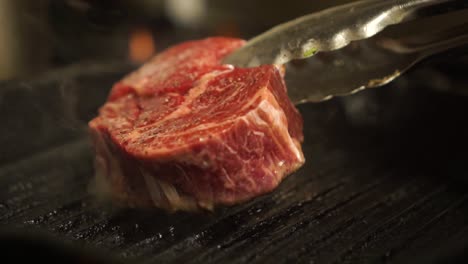 SLOWMO---Tongs-turning-over-steak-cooking-on-a-bbq-pan---CLOSE-UP-detail