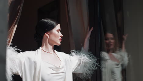 woman in a white bathrobe by the window