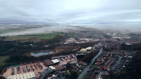 Aerial-footage-of-a-mist-covered-urban-district-in-Yorkshire-UK,-showing-busy-roads-traffic,-factories-and-red-brick-houses