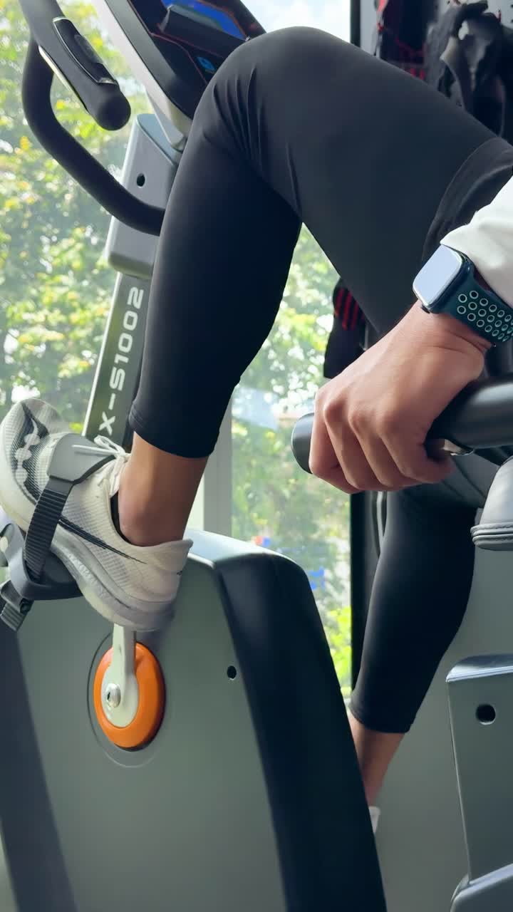 Una persona si allena su una cyclette orizzontale in una palestra ben illuminata, concentrandosi sul movimento delle gambe e sul monitoraggio del fitness.