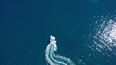 a motor boat traveling through the water in the sun is seen from above