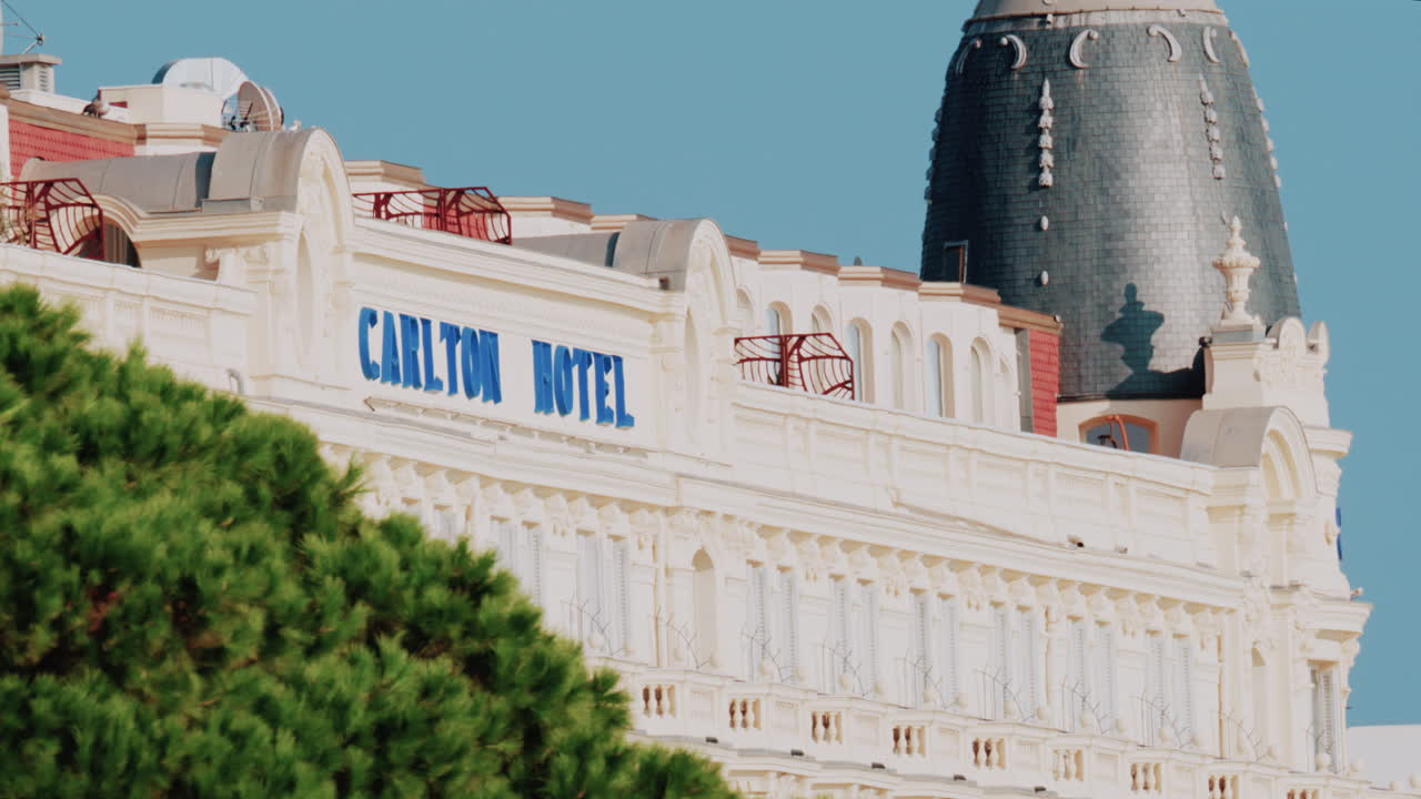 Cannes, France - October 4, 2025: Elegant view of the Carlton hotel surrounded by lush green palm trees under clear blue sky