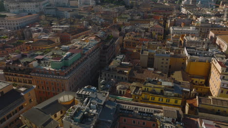 Vista-De-ángulo-Alto-De-Los-Edificios-En-El-Distrito-Urbano,-Volar-Hacia-Atrás-E-Inclinar-Hacia-Arriba-Para-Revelar-El-Paisaje-Urbano-Con-Monumentos-Famosos.-Roma,-Italia