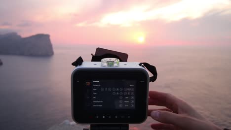 videographer adjust camera settings and nd exposure filter shooting scenic sea landscape at dusk