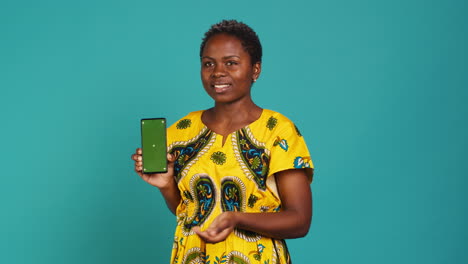 Young-confident-woman-presenting-a-green-screen-on-smartphone