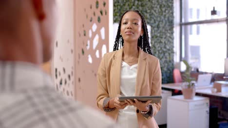 diverse male and female colleagues in discussion using tablet in casual office meeting, slow motion