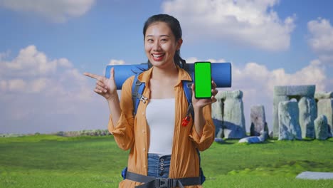 tourist woman holding phone with green screen in front of historical site