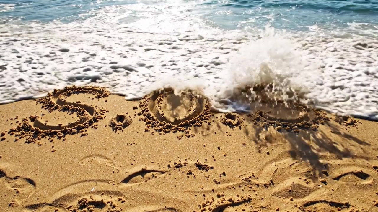 Desperat råb om hjælp: Budskabet 'S.O.S.' ridset i sandet på en strand, omgivet af blide bølger og sollys, der reflekteres i vandet.