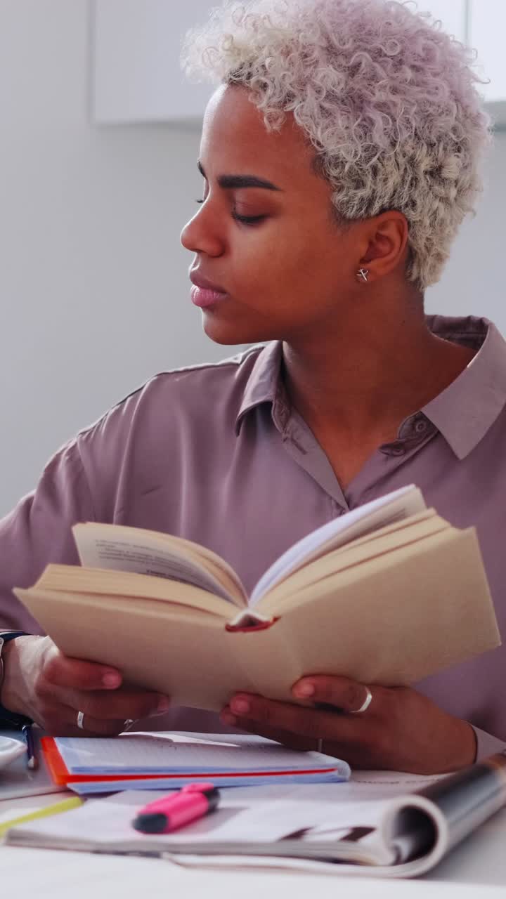Young woman reading aloud from a notebook at a bright modern desk